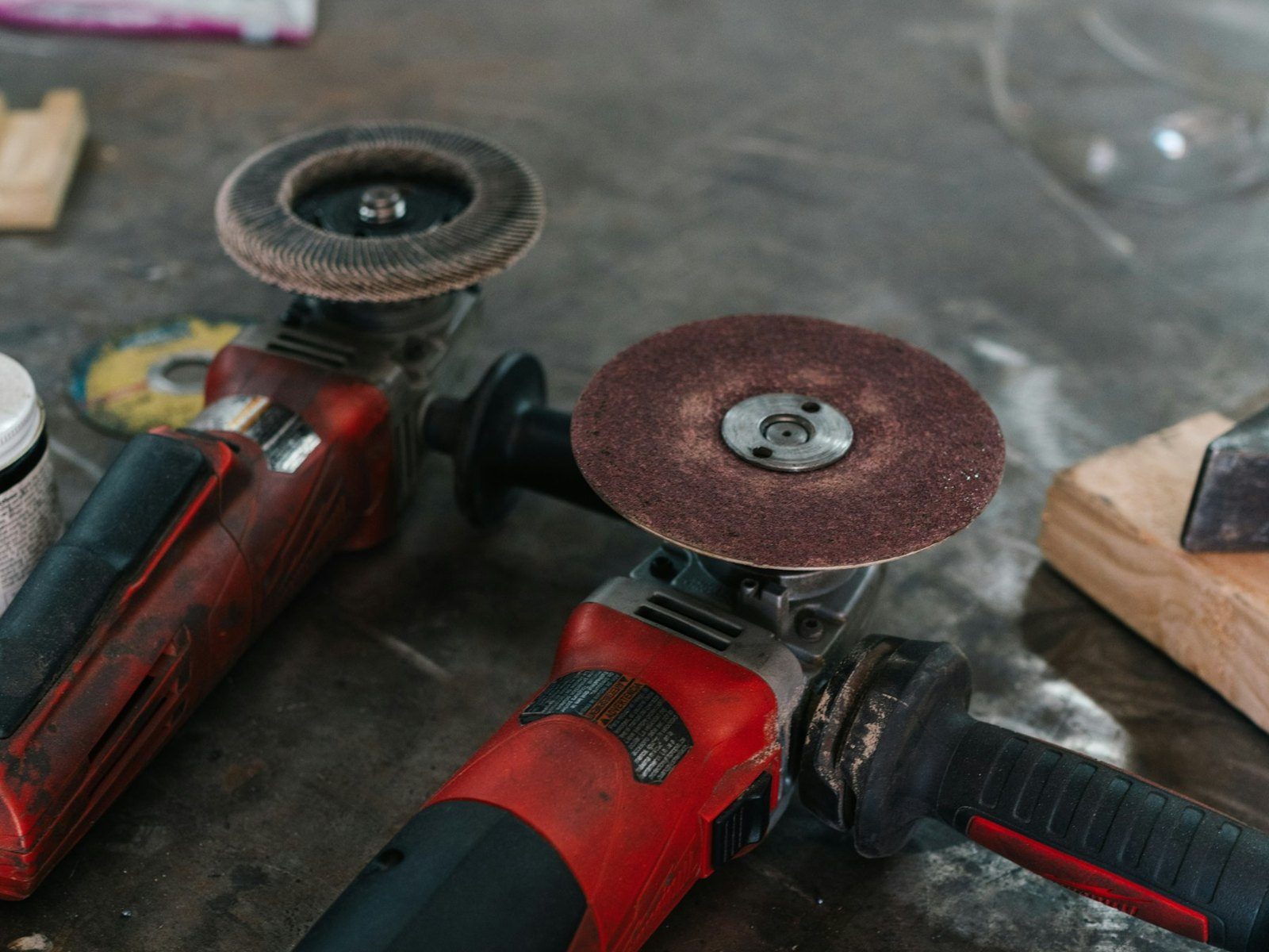 Two well-used angle grinders on a site workbench